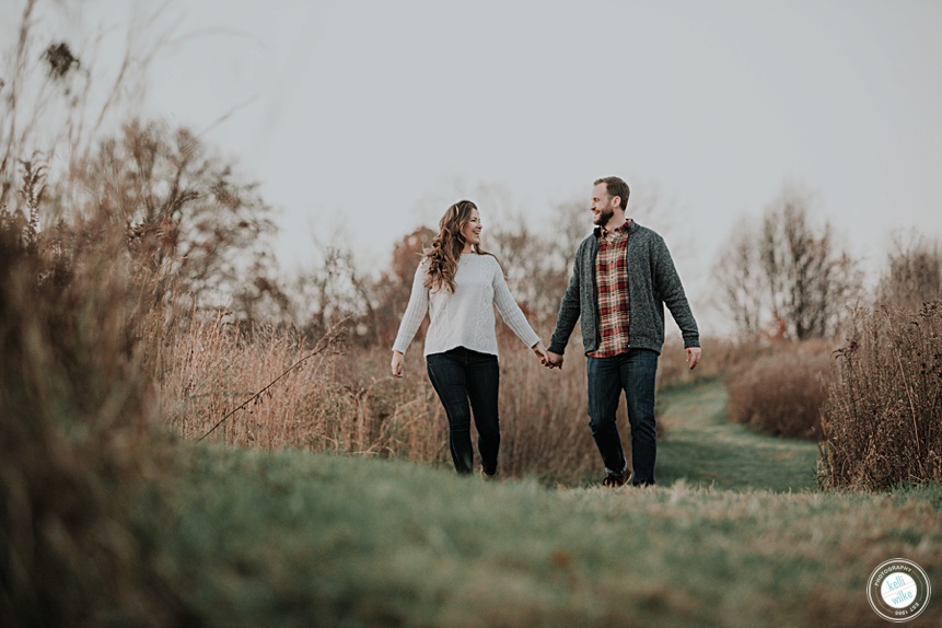 couple walking holding hands in a field at Longwood Gardens in the fall