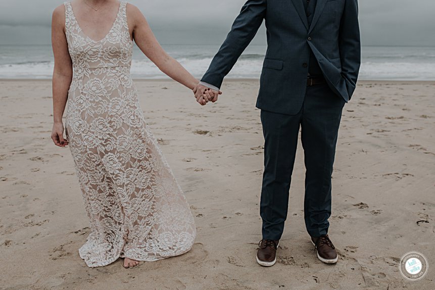 couple holding hands on the beach on their wedding day in delaware