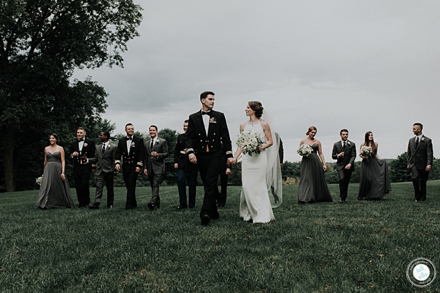 bride groom and wedding party walk across a field at a wedding in delaware