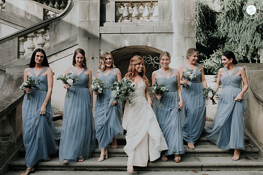 bride and bridesmaids walk down the stairs at winterthur gardens in wilmington delaware