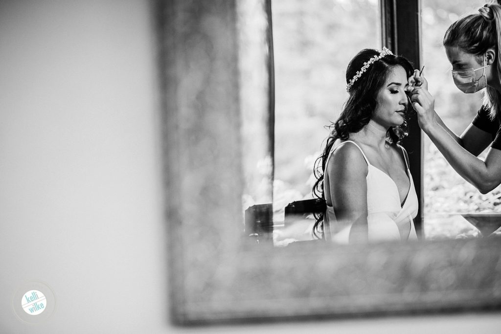 Bride has her makeup done before her wedding by Jackie Scully who is wearing a mask for Covid19 safety at Greenville Country Club 