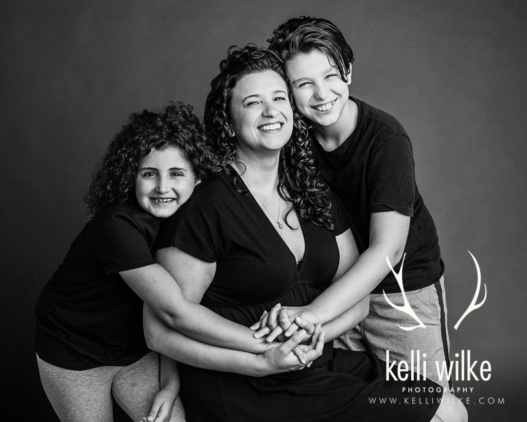 mother with her daughter and son in a black and white portrait by award winning portrait photographer Kelli Wilke