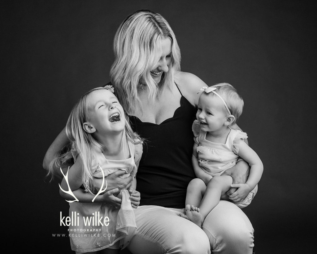 mother with her two young daughters in a black and white portrait