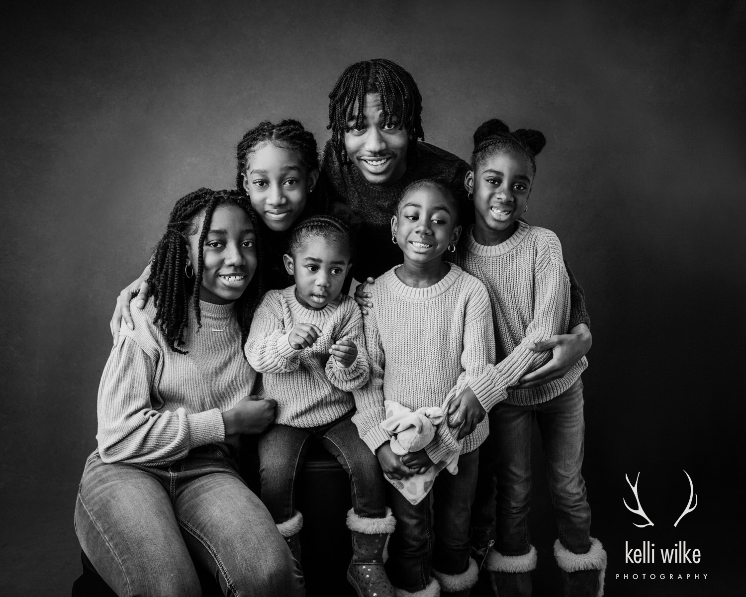 A black and white photo of a family smiling at the camera. 