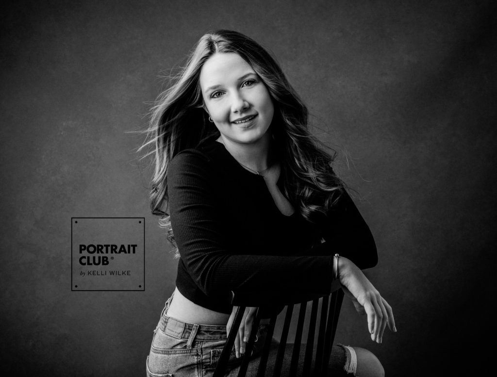 A portrait of a teenage girl sitting on a chair, smiling at the camera during a photo session with Kelli Wilke Photography. 